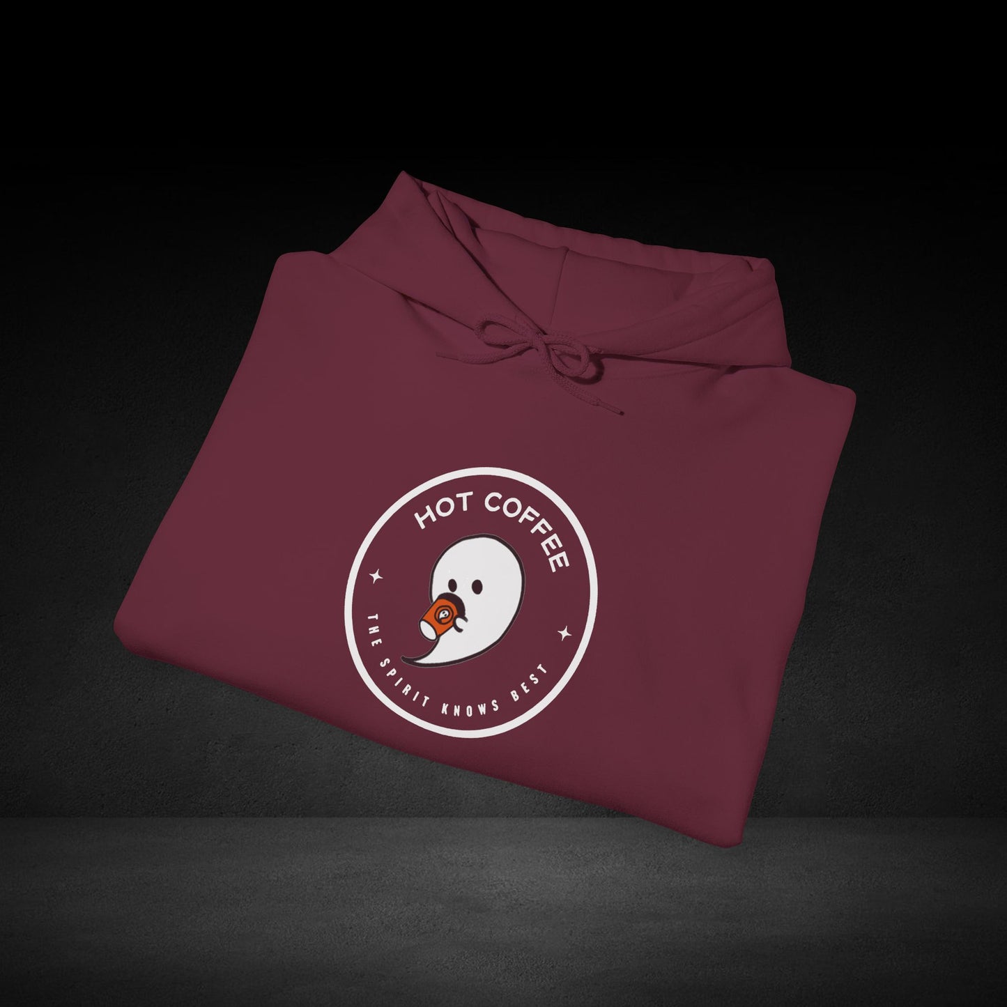 A maroon hoodie with a white circular logo and text on it, placed on a dark surface.