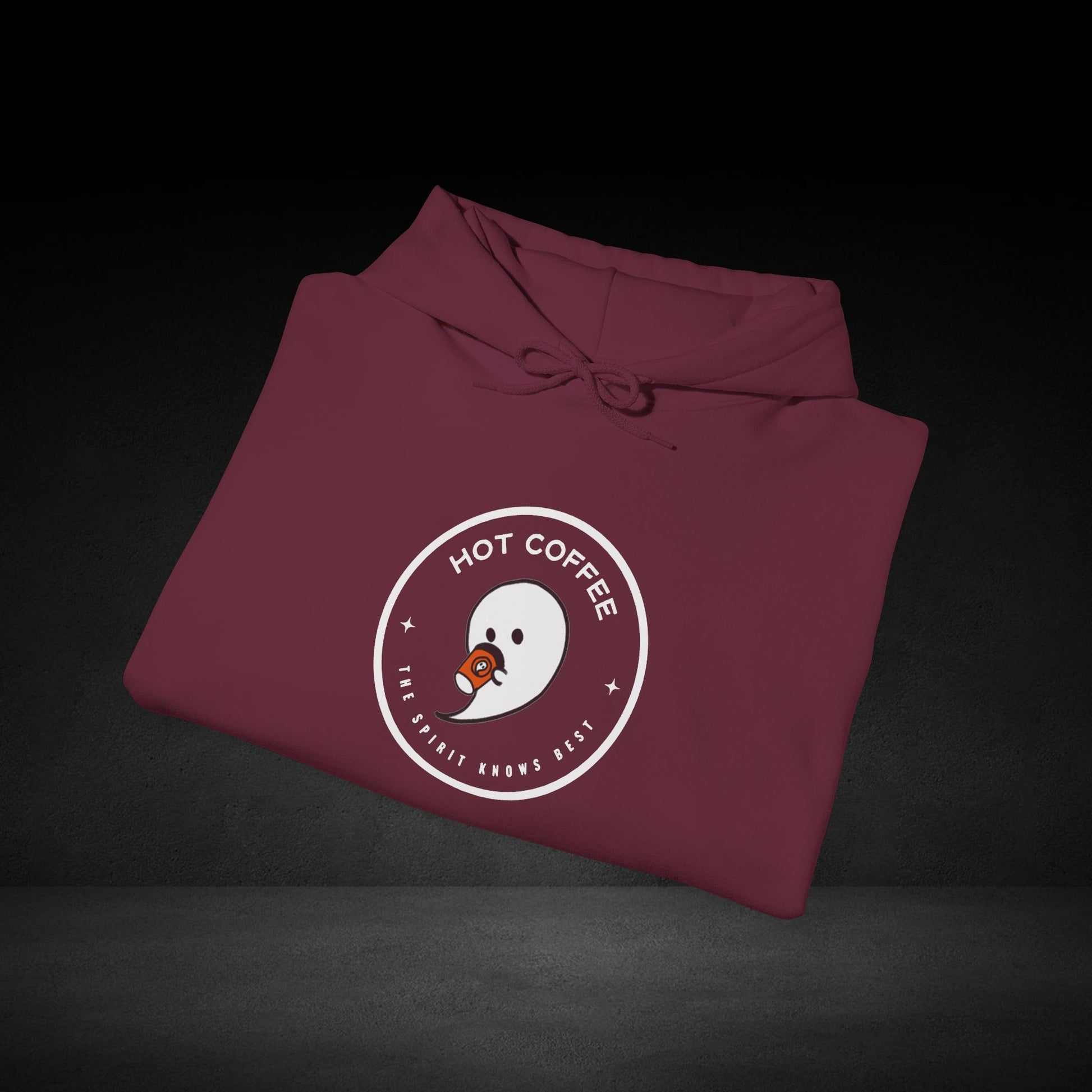 A maroon hoodie with a white circular logo and text on it, placed on a dark surface.