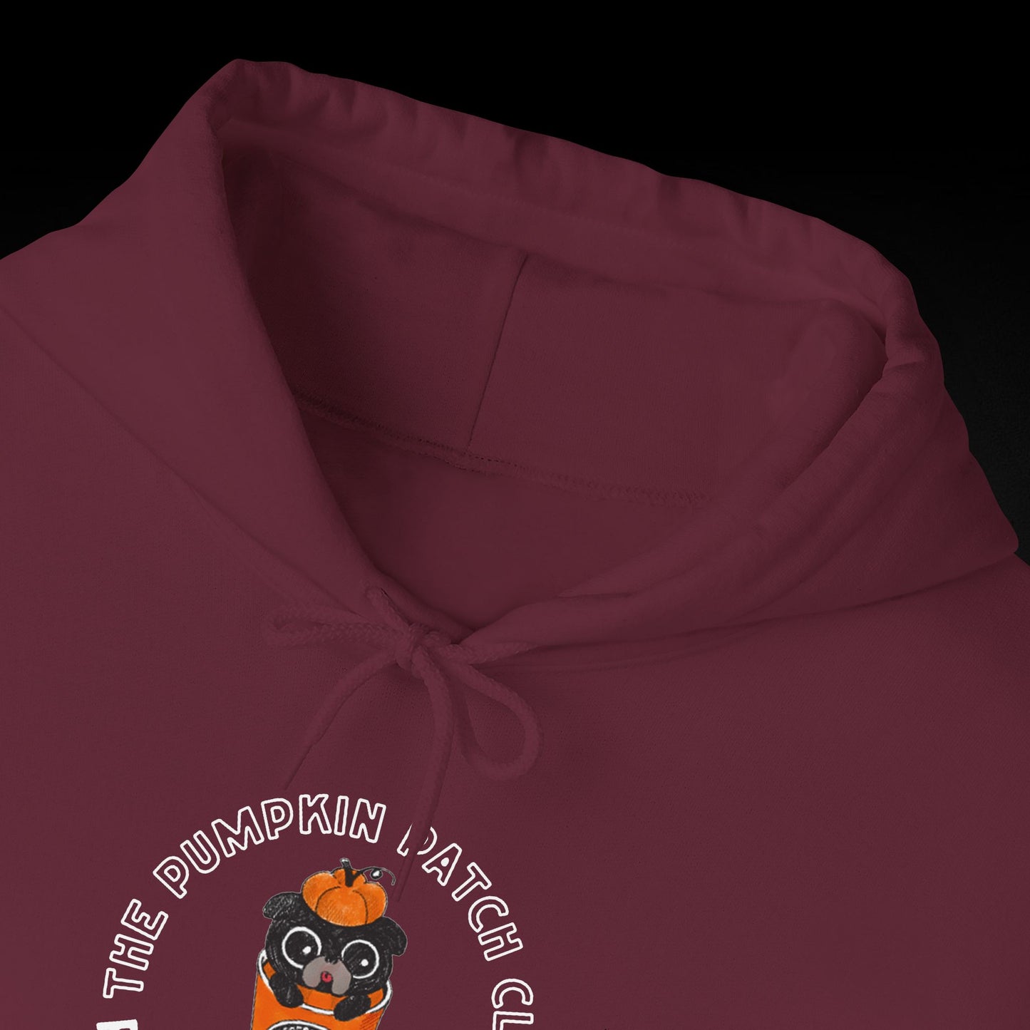 A close-up view of a burgundy hoodie with a graphic design featuring a cartoon character wearing a pumpkin hat.